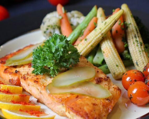 A beautifully plated salmon dish with fresh vegetables and lemon slices, perfect for a gourmet meal.